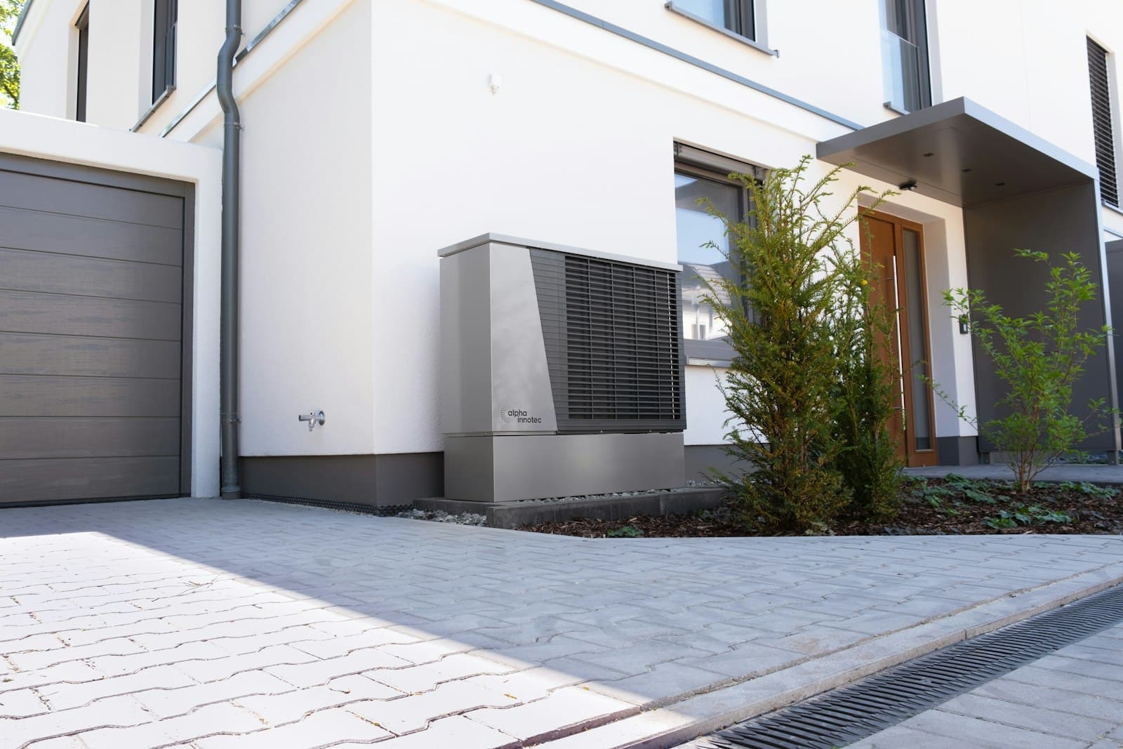 Moderne Luft-Wärmepumpe im Garten vor einem Wohnhaus